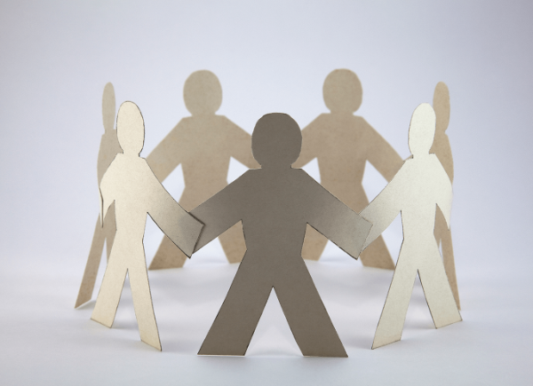 A photo of seven paper figures holding hands in a circle.