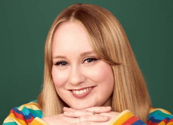 Headshot of someone with long blonde hair in striped jumper smiling