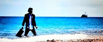 Silhouette of someone looking out over very blue sea from white sand