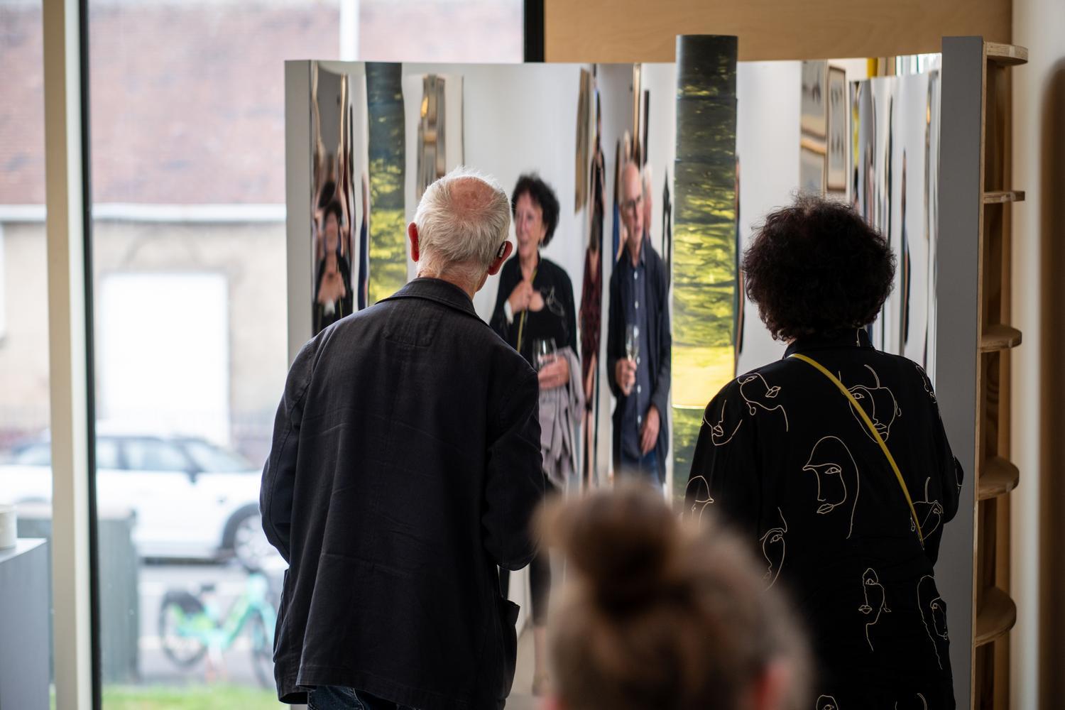 Two people engage with a mirrored art piece