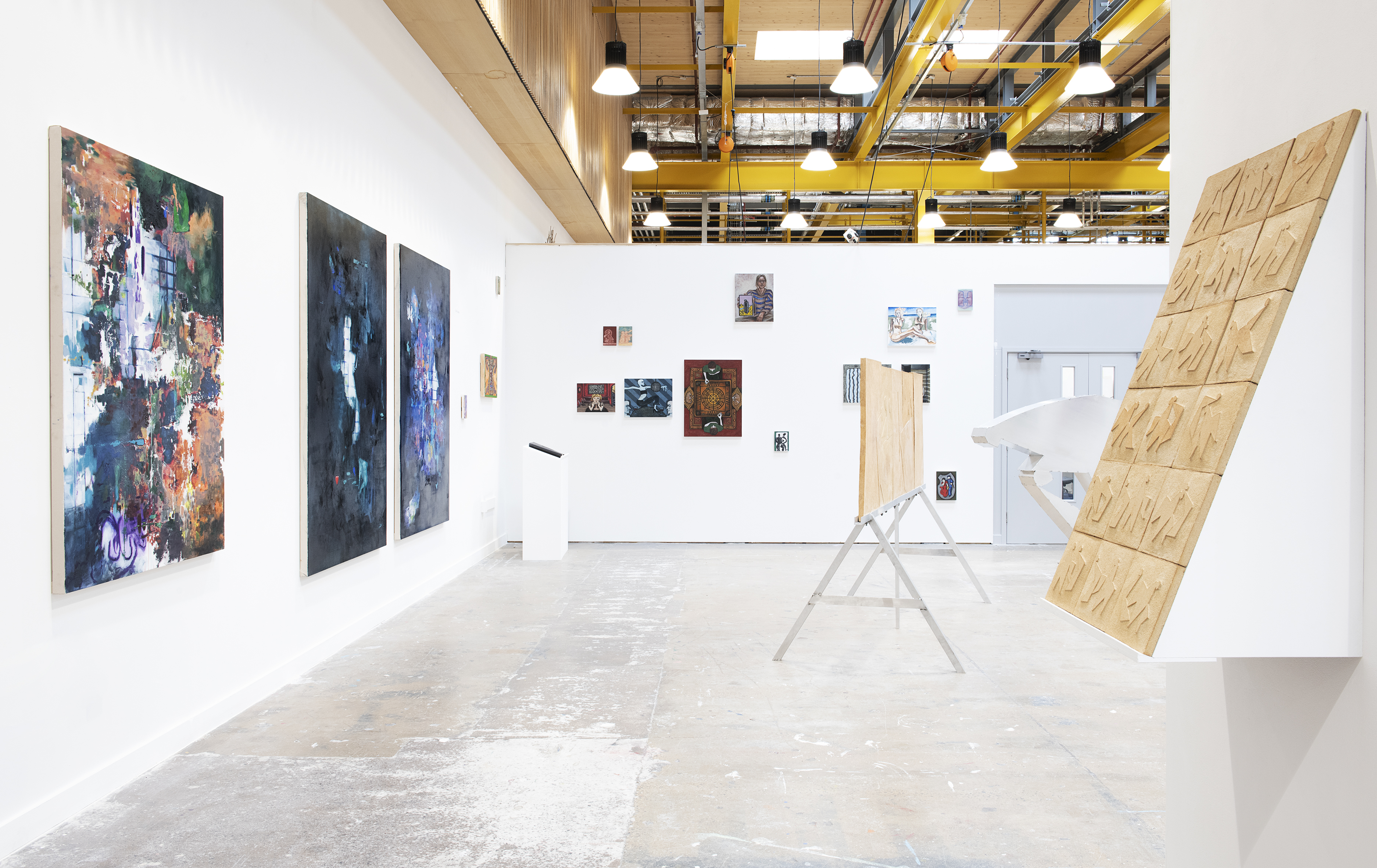 A large, open exhibition space with paintings and sculptures displayed