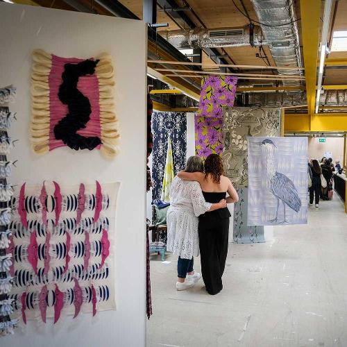 Degree Show visitors with their arms around one another, admiring a piece of work