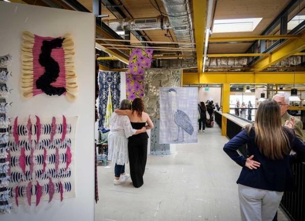 Degree Show visitors with their arms around one another, admiring a piece of work