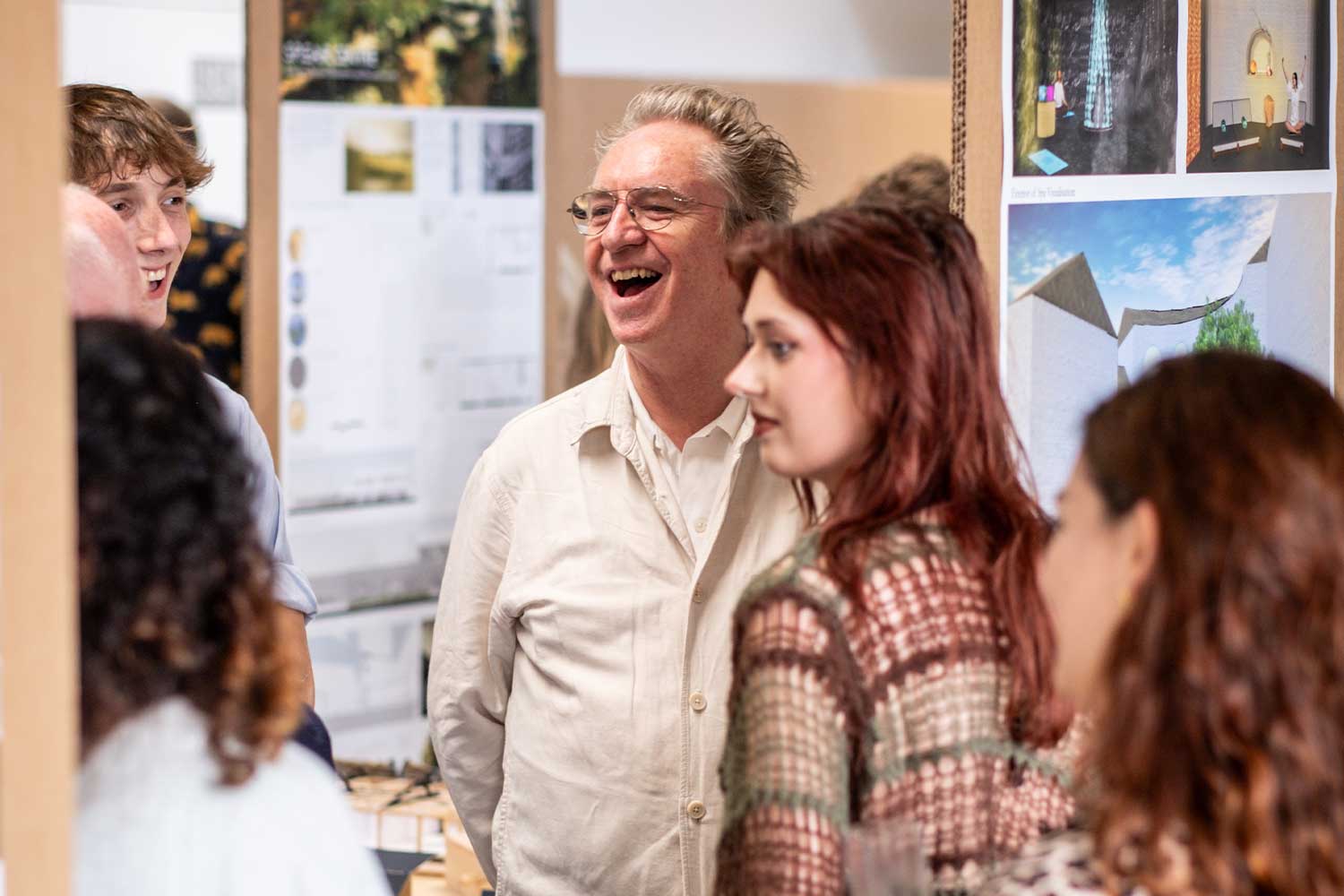 A group of people stand in an exhibition laughing and smiling
