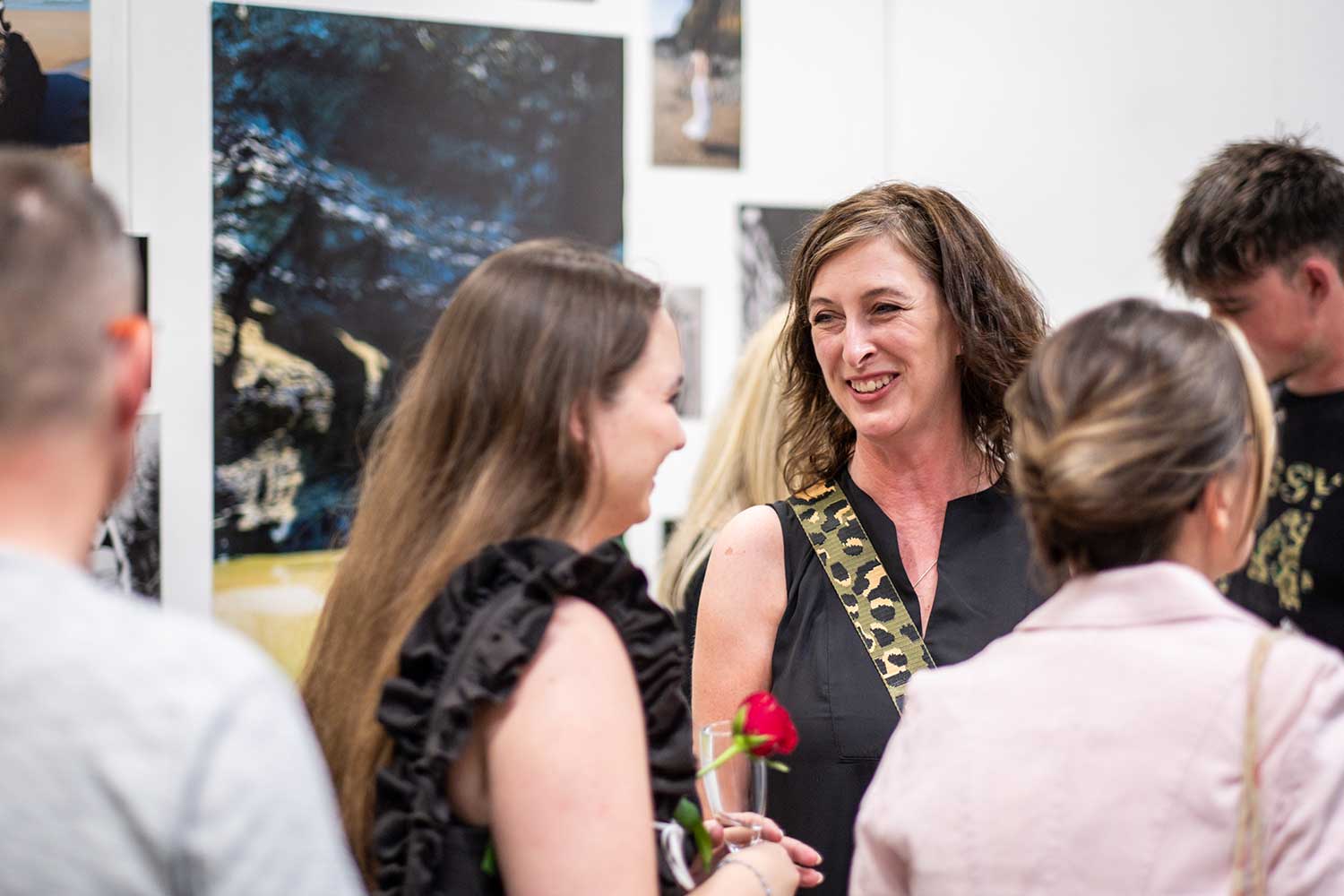 One person turns to another while standing in a crowded exhibition space