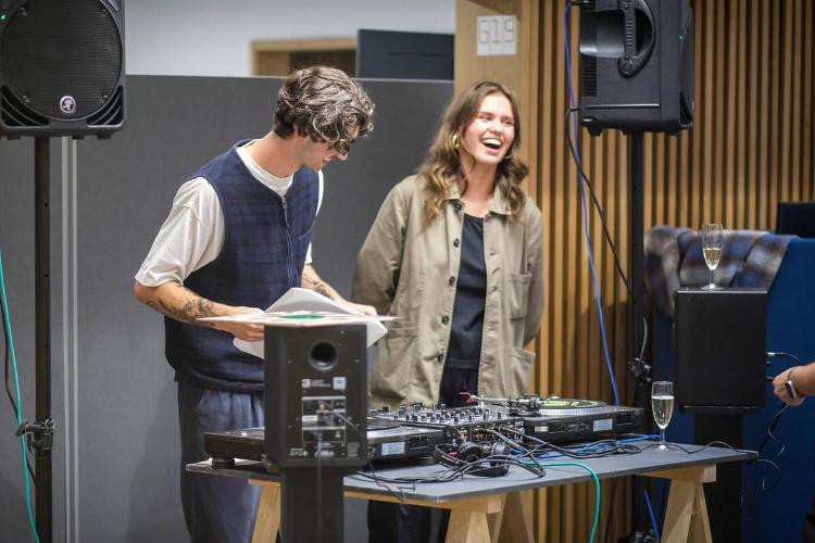 A person standing next to a DJ at an event