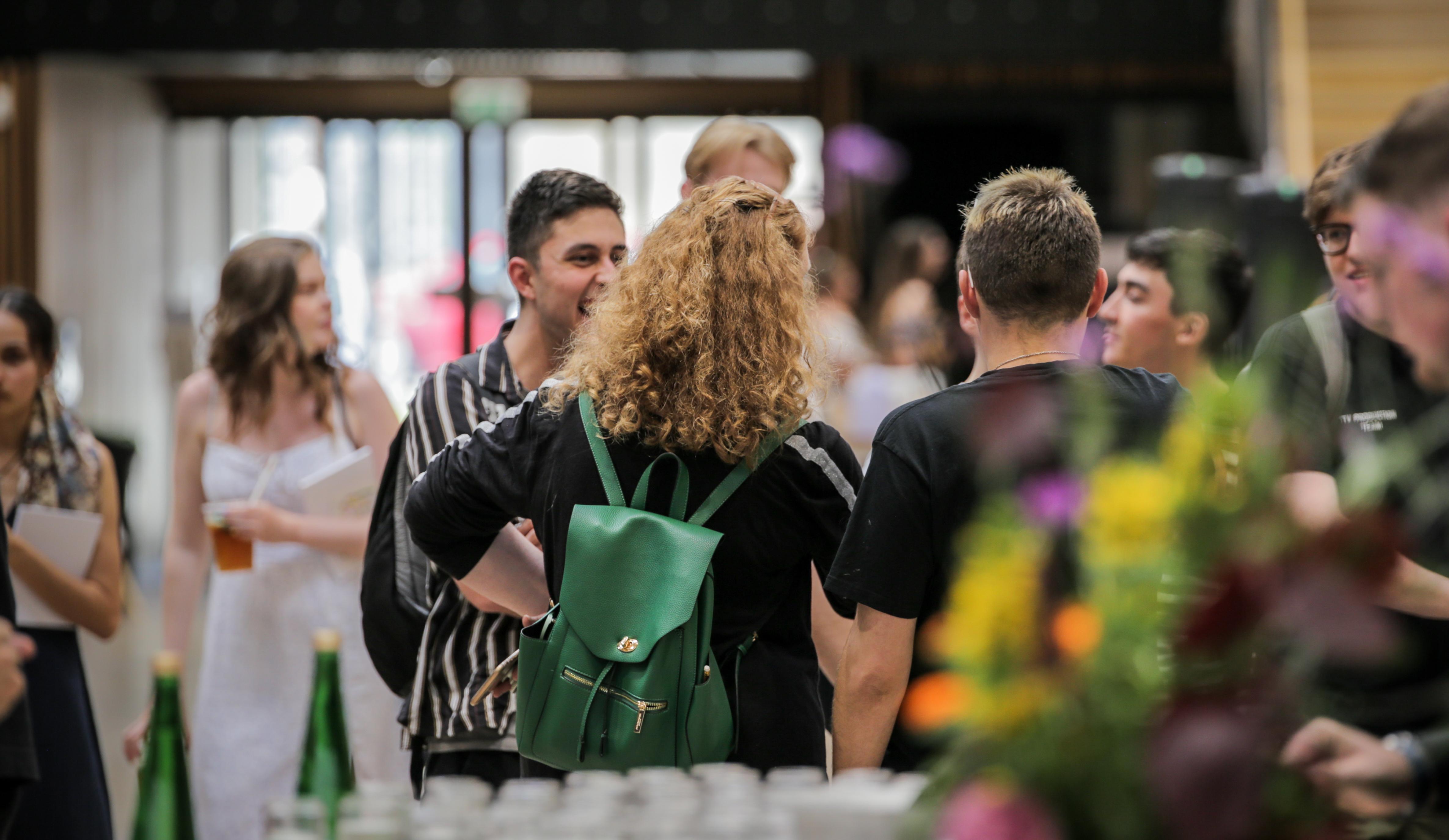 A busy hallway with people standing and talking near a bar