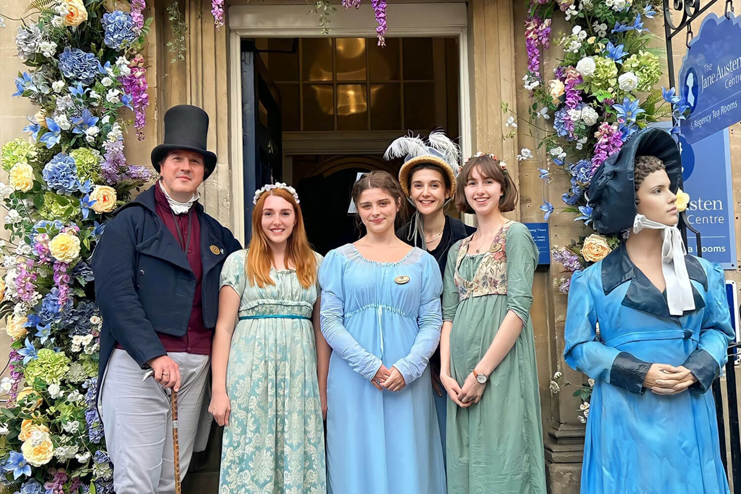 Four people stood in front of the Jane Austen centre in Bath, wearing regency clothing
