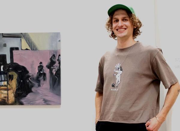 A young man stands in front of an abstract painting in a white gallery2