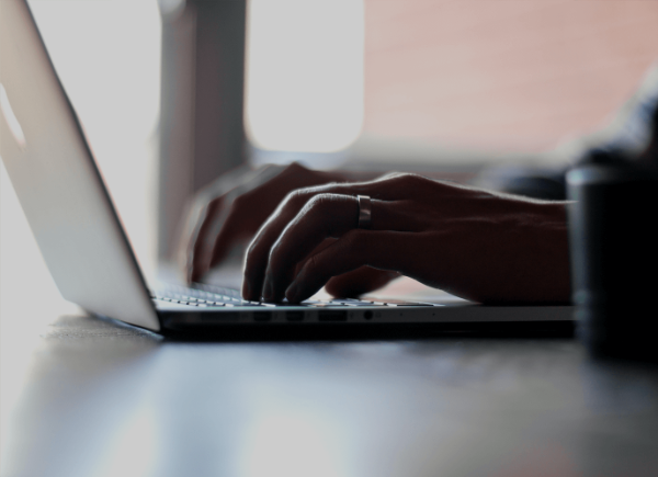  A man's hands typing on a laptop.