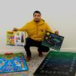 Kamal Ali crouches down behind the two interactive prayer mats he has created, holding the boxes for each
