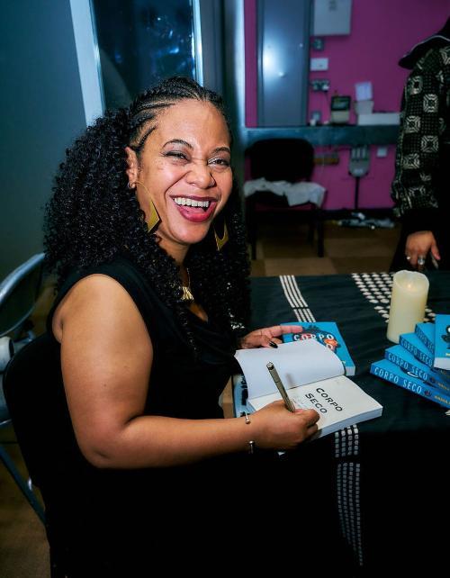 Nadia Maddy smiling as she signs one of her books