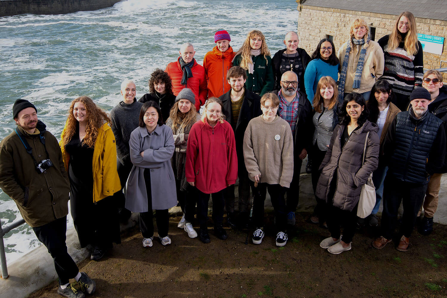 Group of people standing near harbour waters and Cornish buildings