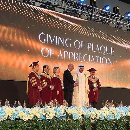 Senior staff members stand on a stage at graduation