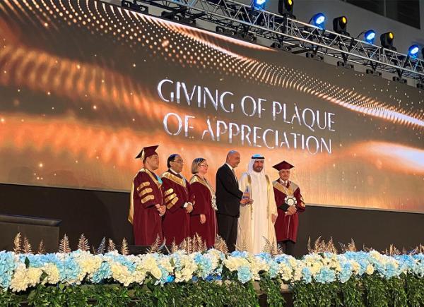 Senior staff members stand on a stage at graduation