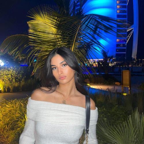 a girl stood in front of palm trees at nighttime