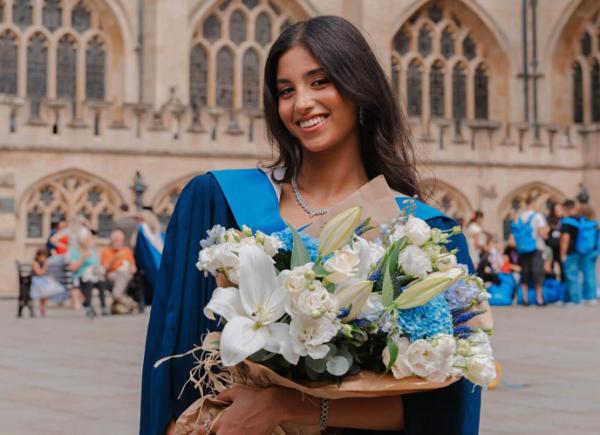 a girl on her graduation day holding a big bunch of flowers