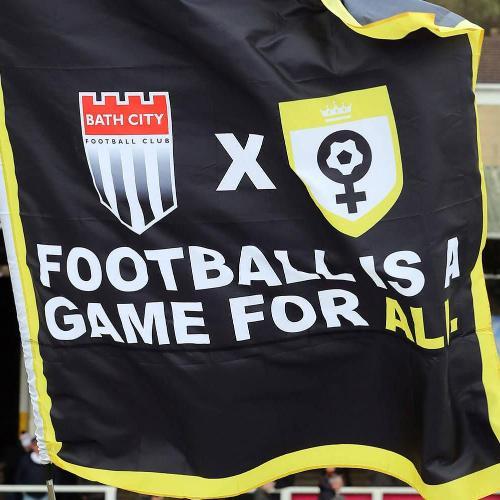 A flag showing the Bath City and Her Game Too badges with the words Football is a game for all written on it