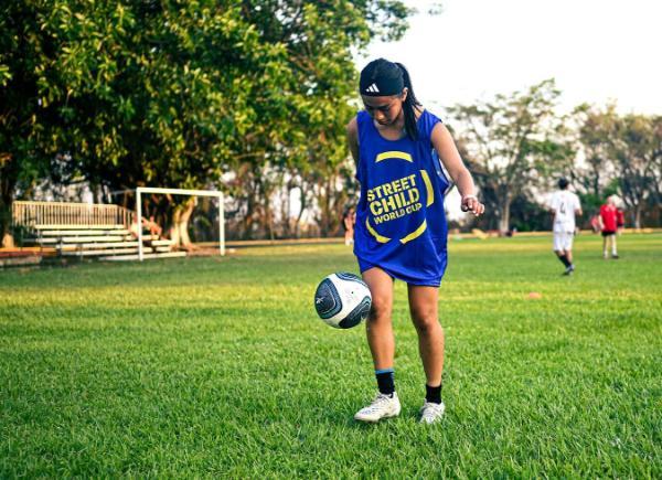 a child kicking a football on a football pitch