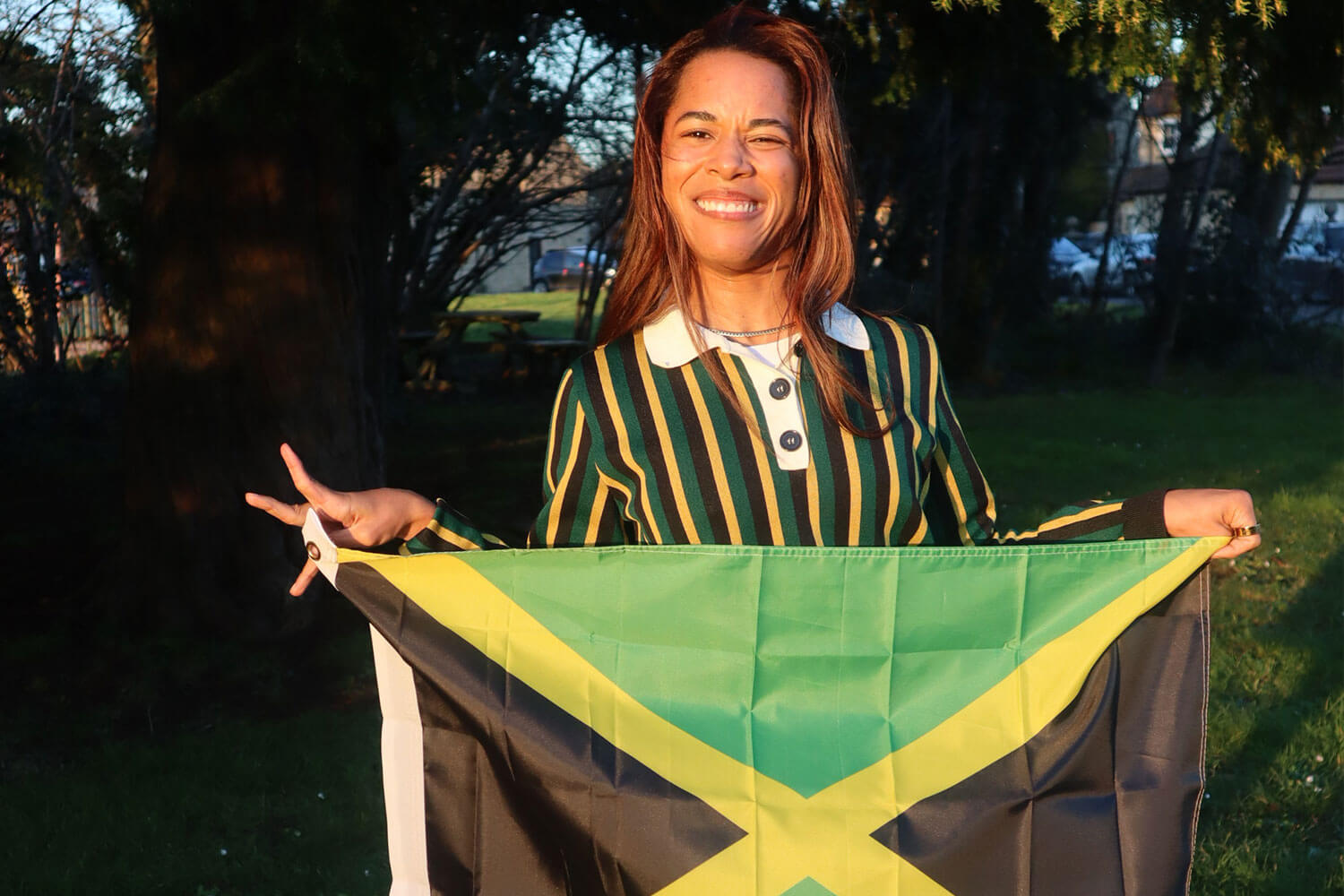 a girl smiling and holding a Jamaican flag