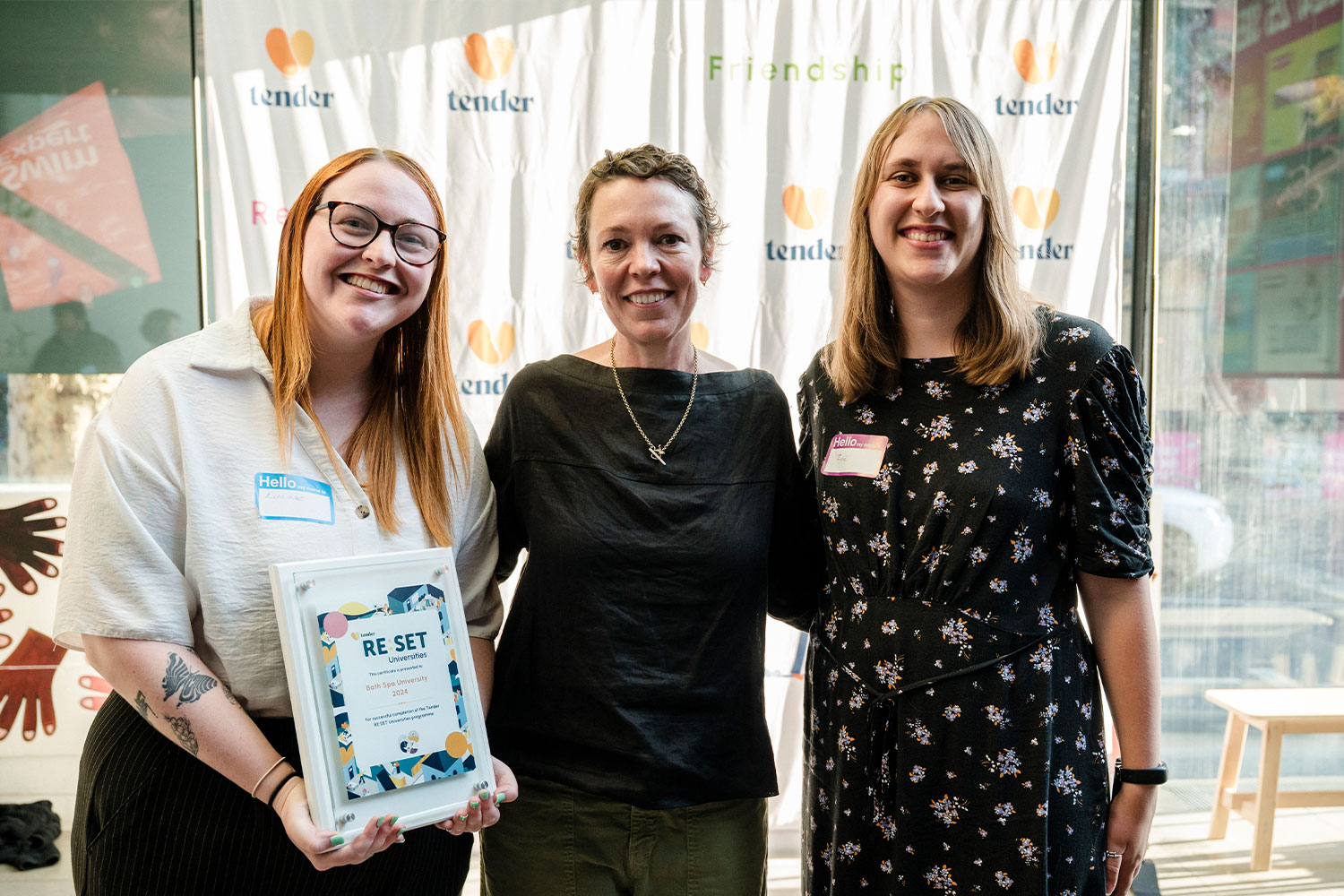 Three women posing for the camera holding a Tender award