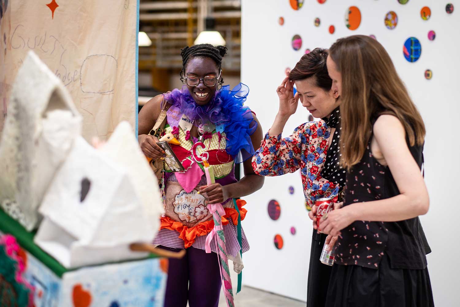 Three people stand and look at a colour exhibition piece