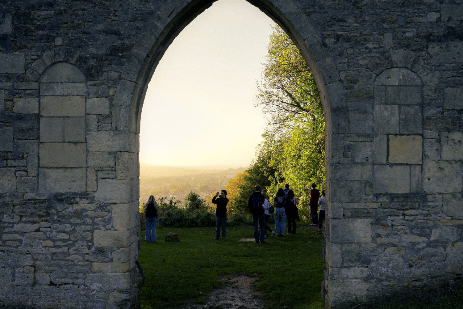 Students stood in an archway on a walk in the sunshine