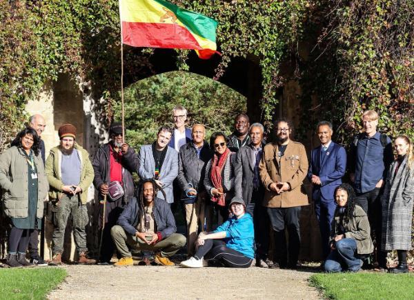 A large group of people stood in front of a leafy archway in the sunshine