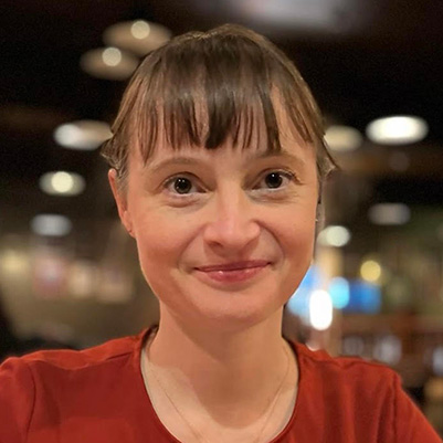 A Bath Spa staff member in a red top smiling at the camera