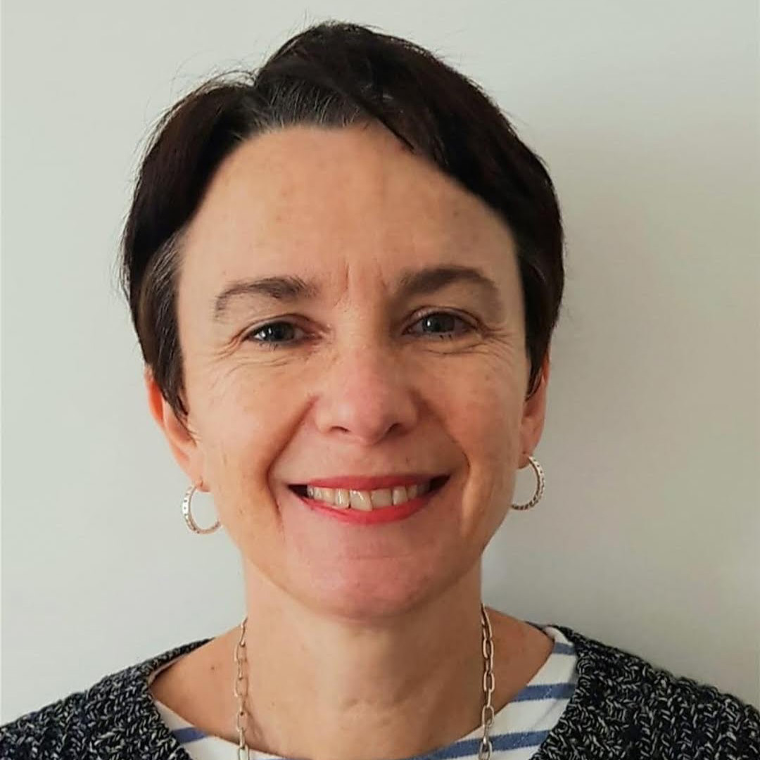 A profile picture of a woman standing against a white background.