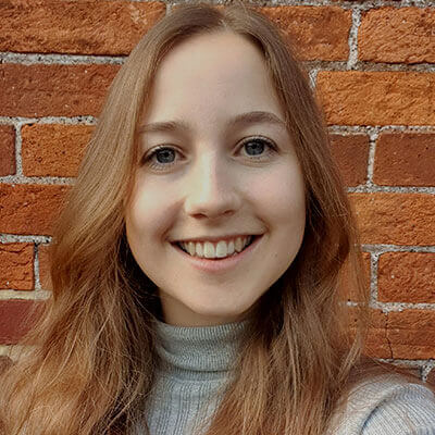 A girl with light brown hair smiles at the camera as she takes a selfie