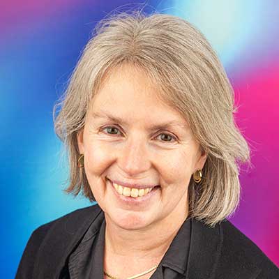 A person with a short grey-toned bob smiles at the camera