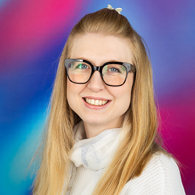 Headshot of someone with long blonde hair in white shirt smiling