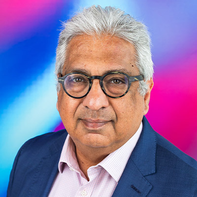 A person with cropped grey hair and dark glasses