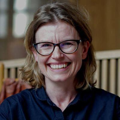 A woman with glasses smiles at the camera