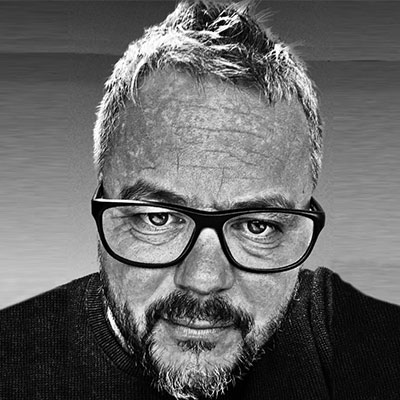 Black and white sylised headshot of person with glasses and short light hair