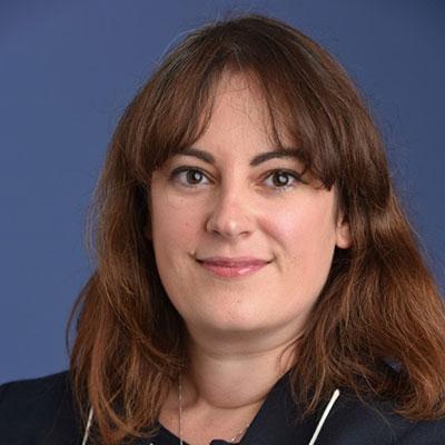 A woman with long brown hair and dark brown eyes in a blue suit.