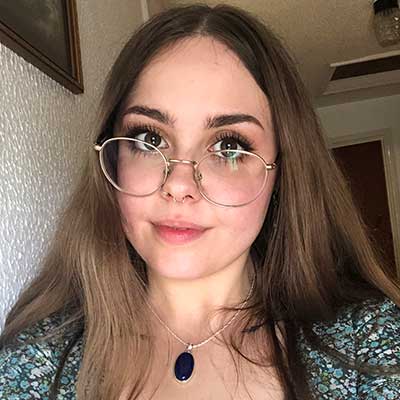 A person wearing gold glasses takes a selfie