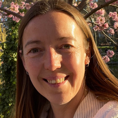 A Bath Spa staff member standing in front of a rose bush