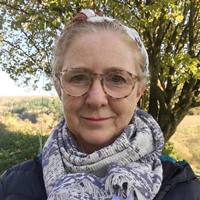 Older woman in round glasses with a blue and white patterned scarf.