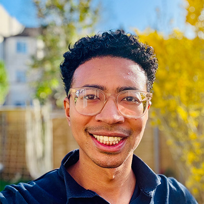 Person with short dark hair and glasses smiling at camera