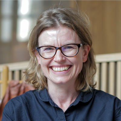Person with shoulder length blonde hair and glasses smiling