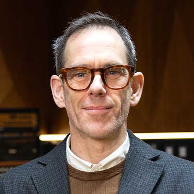 Person in dark blue blazer with glasses and short hair