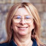 Smiling woman wearing gold rimmed hexagonal glasses