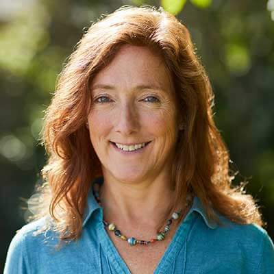 A person with shoulder-length hair smiles at the camera