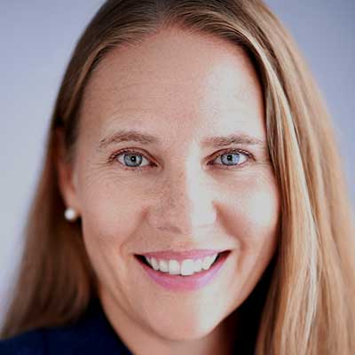 A person with long, light brown hair smiles at the camera