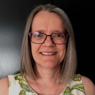 A woman wearing glasses smiles at the camera