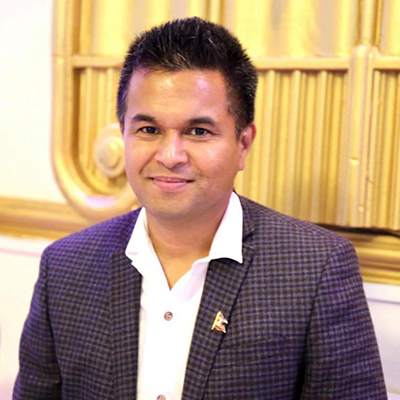 A person wearing a white shirt and grey suit looks at the camera