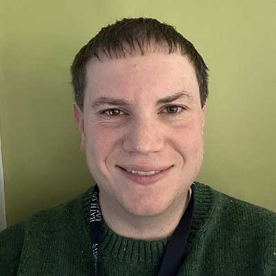 A person with short hair smiles at the camera