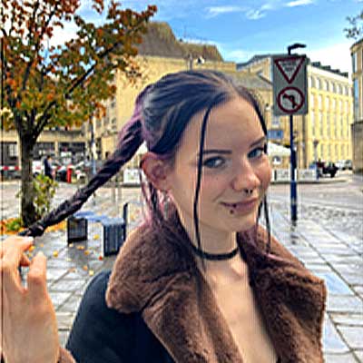 A person wearing a brown fluffy coat looks at the camera